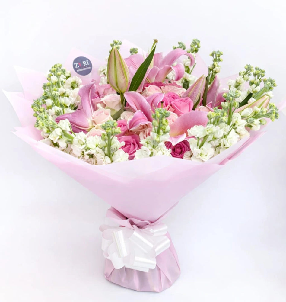 Blooming Grace bouquet featuring pink roses, pink lilies, and white matthiola, arranged by Zuri Blooms