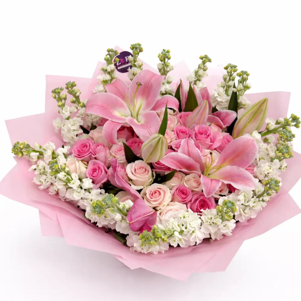 Bouquet of pink Lilies and Roses and white flowers wrapped in pink paper on a white background