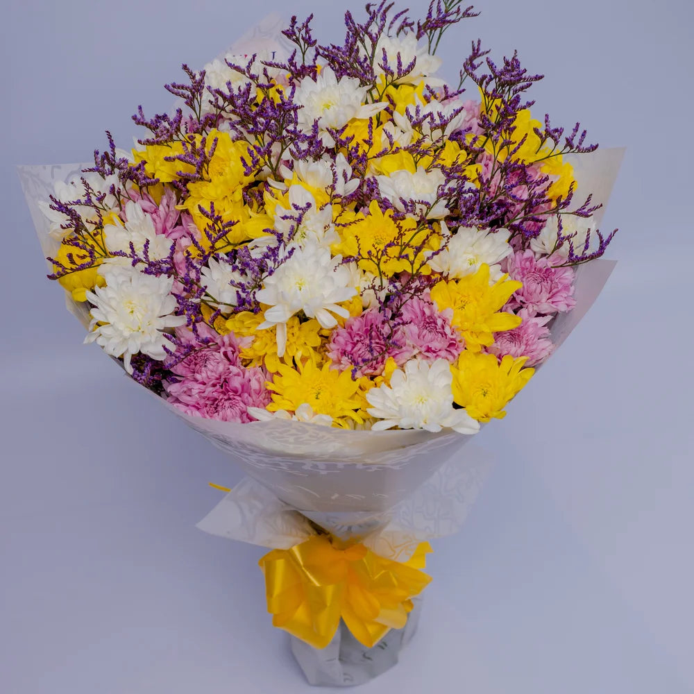 Golden Radiance bouquet featuring yellow, white, and pink mums with purple Limonium, arranged by Zuri Blooms