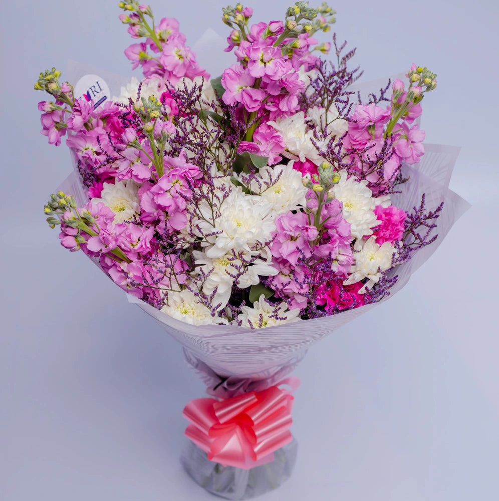 Majestic Petals bouquet featuring matthiola, white mums, pink carnations, and purple limonium Wrapped, arranged by Zuri Blooms