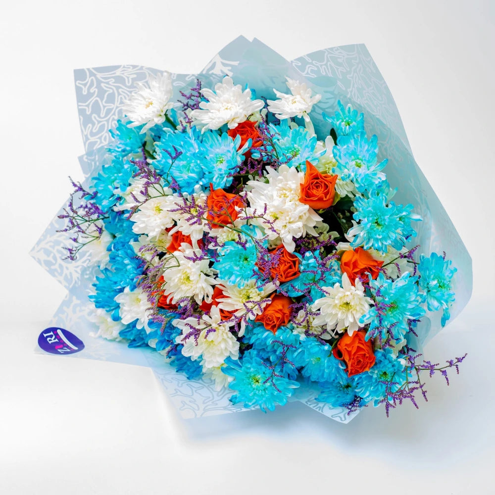 Sunset Reverie bouquet featuring orange roses with white and blue mums and purple limonium, arranged by Zuri Blooms